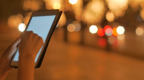 Usando o tablet em pé na calçada