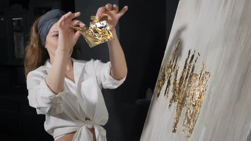 Attraktive Künstlerin, die Blattgold auf ihr Kunstwerk anwendet