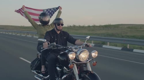 Couple rides motorcycle on highway in the desert ,man with helmet and sunglasses at wheel and woman