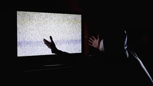 Silhouette Man in Hood and Medical Mask Watching TV Interference with Hands Up