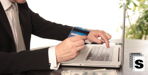 Man Types on Laptop with Credit Card in Hand