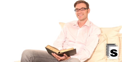 Man Reading Book on Couch Indoors