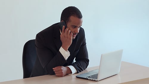 Businessman Talks on Phone and Works on Laptop
