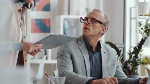 Businesswoman Showing and Discussing Report with Male Manager