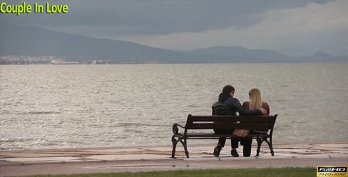 Couple Sits on Bench Looking out to Sea
