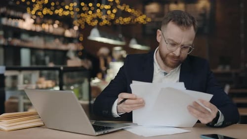 Businessman Checking Corporate Paperwork Correspondence While Sitting at Cafe