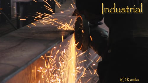 Worker Grinding Metal with Sparks in Dark Factory