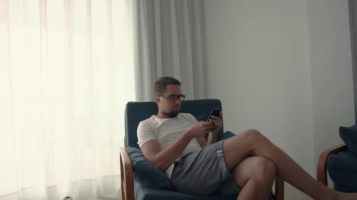 Typ im Stuhl surft im Internet auf dem Smartphone.