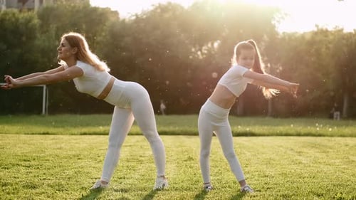 Woman and Child Exercising Together on Grassy Field