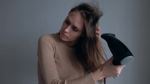 Woman Dries Wavy Brown Hair with Hair Dryer