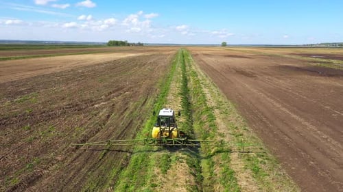 Tractor Spraying Pesticides on Vegetable Field with Sprayer