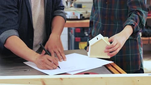 Close up of Two Carpenter workers are planning construction of built-in furniture in wood workshop