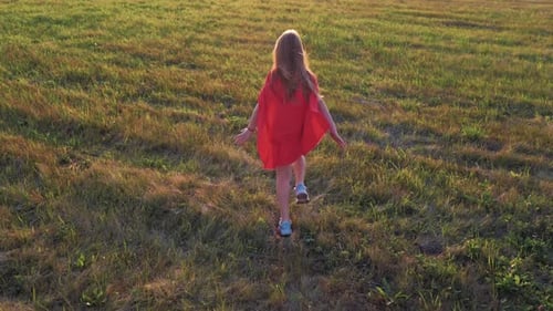 Child Runs Through Grassy Field with Red Cape