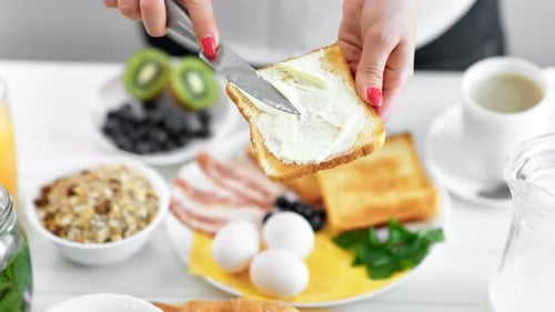 Hands Spreading Butter on Toast for Breakfast