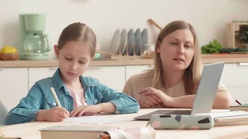 Girl Doing Schoolwork with Mother in Kitchen