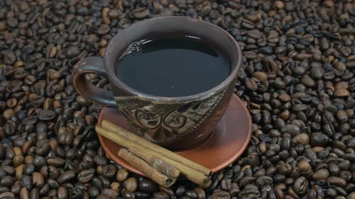 Coffee Cup and Cinnamon Sticks on Coffee Beans