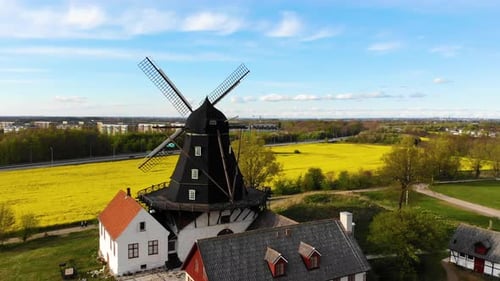Zumbido que rodea un molino de viento sobre un campo verde con una marca de raps en el frente. Suecia primavera