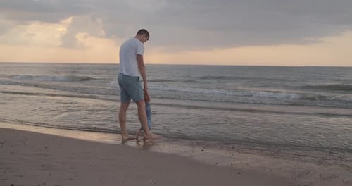 Vater hilft seinem Kleinkindsohn, die ersten Schritte am Strand zu machen