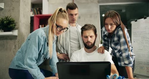 Team Collaborating Around Laptop in Modern Office