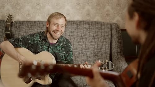 Man Playing Guitar for Another Musician Indoors