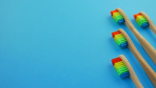 Wooden Toothbrushes with Colored Bristles on Blue Background