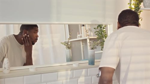 Man Examining Face in Bathroom Mirror