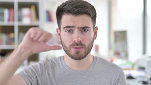 Portrait of Thumbs Down By Disappointed Young Man