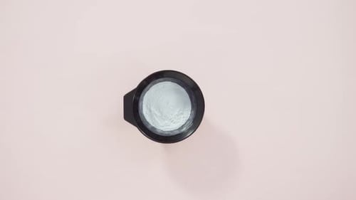 Hair Color Dye Powder in a Black Plastic Mixing Bowl on a Pink Background