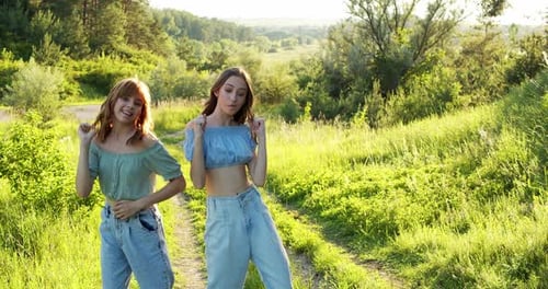 Two Carefree Girls in Stylish Summer Looks Dancing Staging Synchronously