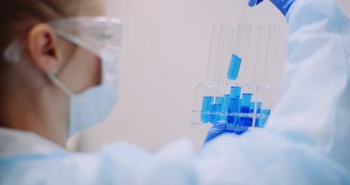 Scientist Removing Blue Liquid Sample from Test Tube Rack