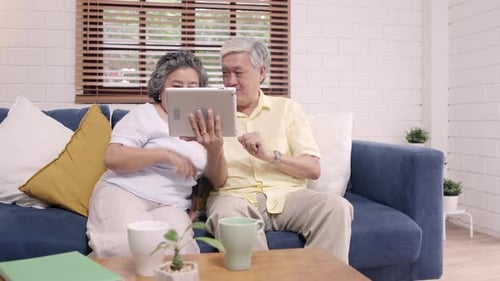 Senior Couple Enjoying Tablet Together on Sofa