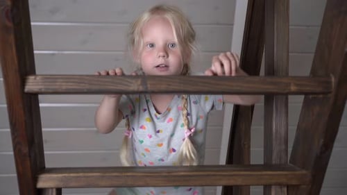 Smiling Girl Playing on Wooden Stairs Indoors