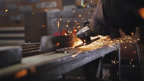 Las chispas salen volando de la amoladora en manos de un mecánico que muele una pieza metálica en un taller de reparación de automóviles