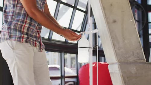Mixed race male cafe worker wearing face mask disinfecting hands