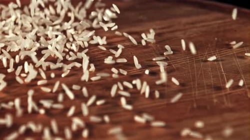 Dry Rice Falling onto Wooden Table