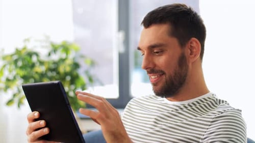 Young Adult Man Uses Tablet at Home