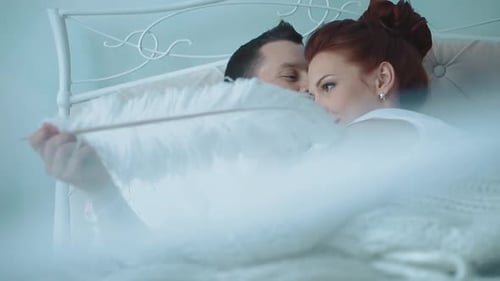 Junges schönes Paar ruht sich im Bett aus und kitzelt ihre große Feder 2 Zeitlupe