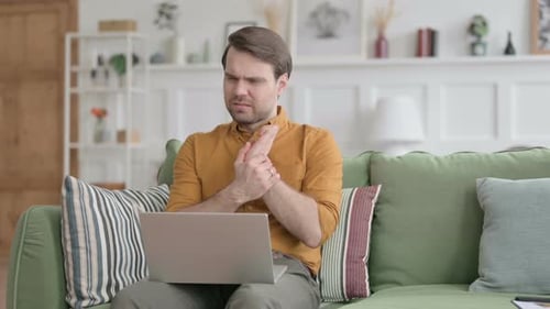 Man Experiencing Wrist Pain While Working on Laptop
