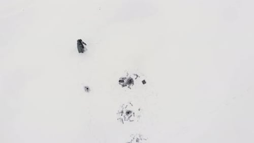 Man is drilling ice with ice drill on frozen lake