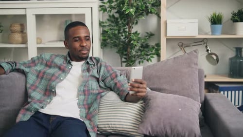 Man Video Chatting on Smartphone While Relaxing on Couch
