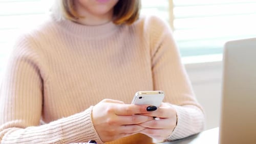 Young Woman Using Smartphone at Desk Indoors