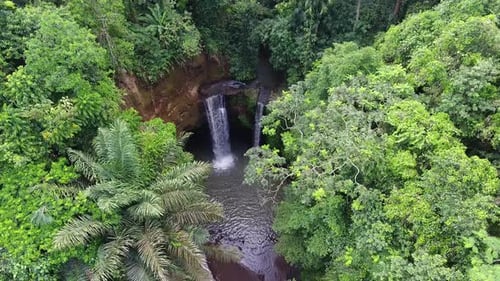 High waterfall with pond hidden in the jungle, top down drone shot