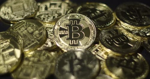 Echte goldene Münzen mit Bitcoin-Logo auf schwarzem Hintergrund