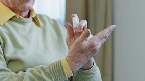 Senior Sprays Hand Sanitizer on Hands