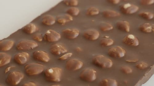 Close-up of milk chocolate with whole hazelnuts 4K 2160p 30fps UltraHD tilting footage - Fine textur