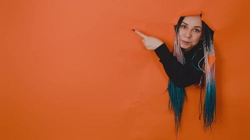 Woman Points Out of Hole in Orange Wall