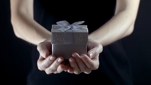 Hands Presenting a Small Gift Box with Ribbon