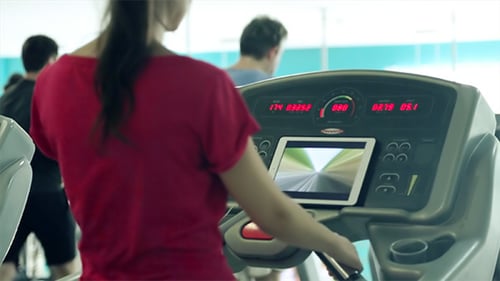 Woman Exercising on Treadmill with Tablet in Gym