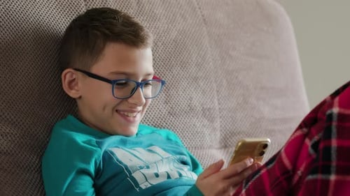 Boy Enjoys Mobile Phone on the Couch