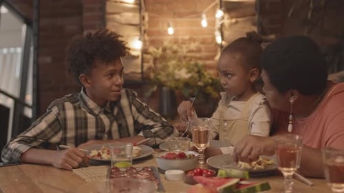 Family Eating and Talking at Dinner Table Inside